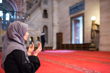 Muslim woman in headscarf and an hijab prays