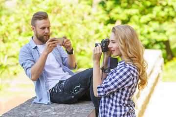 Man and woman taking photos with a camera and a smartphone.
