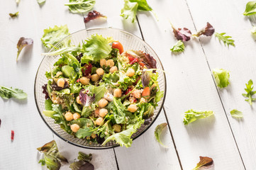 Bowl of salad with vegetables and greens on rustic background 