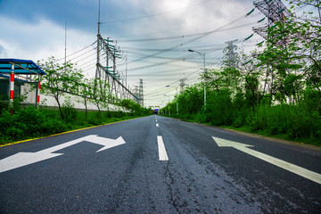 Highway with large high voltage towers under the blue sky white clouds