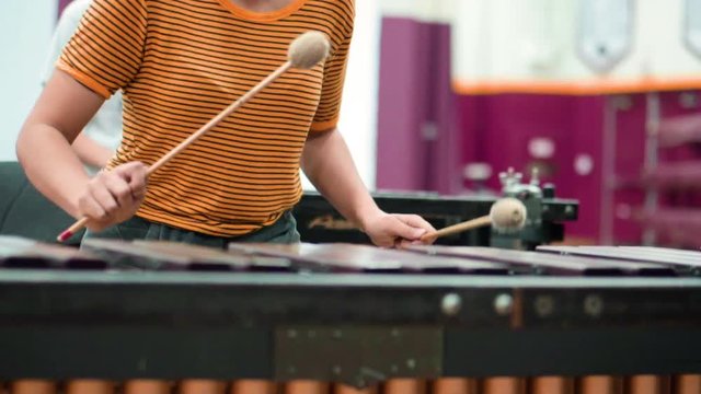 Female high school student playing marimba during percussion rehearsal.