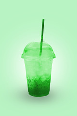 Green juice with ice in a plastic glass with clipping path.