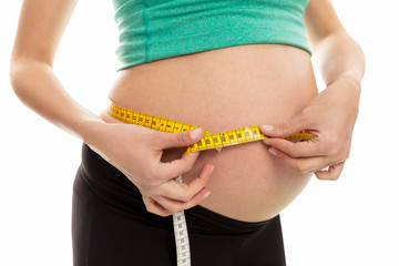 A pregnant woman measures the abdominal circumference. Late term of pregnancy. Close-up. Isolated on a white background.