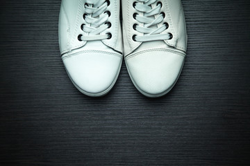 White sneakers on a black wooden background.
