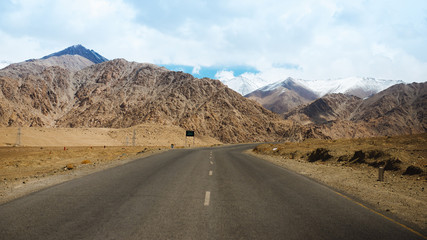 Fototapeta na wymiar Straight road leading towards a snow capped mountain in leh, ladakh, india.