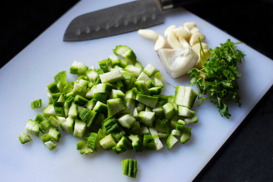 Chopped ridge gourd, turai or dodka, on a chopping board with a knife.