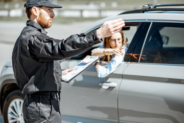 Policeman showing on the road sign while writing out fine for violation of traffic rules for a...