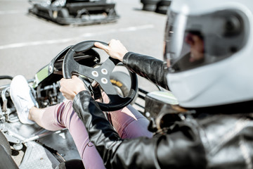 Young woman in protective helmet driving on the go-kart at the track outdoors - obrazy, fototapety, plakaty