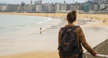 Obraz premium Girl looking at the beach full of people in the city of San Sebastian, Basque Country