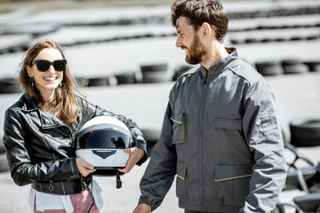 Happy instructor in sportswear with young woman driver on the go-kart track outdoors - obrazy, fototapety, plakaty