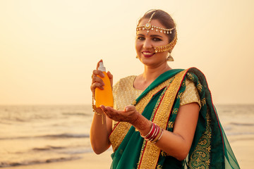 portrait of a beautiful smiling snow-white smile indian woman in a green traditional sari holding...