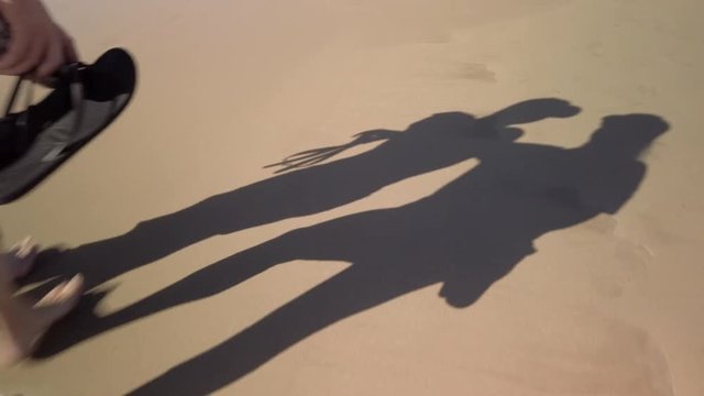 Mom and son shadows walking along a sandy beach