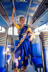 portrait indian beautiful Caucasian woman in traditional blue dress.hindu model with golden kundan jewelry set bindi earrings and nose ring piercing nath fashion photoshoot in bus