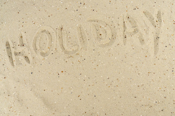 The word holiday written in the sand of a beach