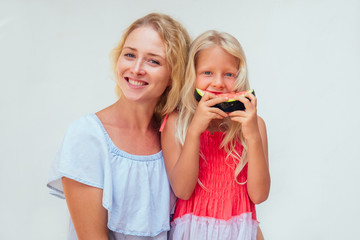 Happy blonde mother and her daughter enjoy making and drinking smoothies together in Bali. caucasian family in the summer ropical vacation drinking fresh green vegetable juice in glass smoothie jar