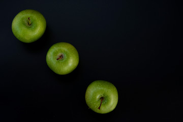 Three green apples on a black background. The insulation on the black. Fruits green apples.Healthy and healthy food. fruits.