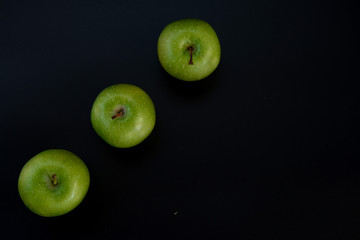 Three green apples on a black background. The insulation on the black. Fruits green apples.Healthy and healthy food. fruits.
