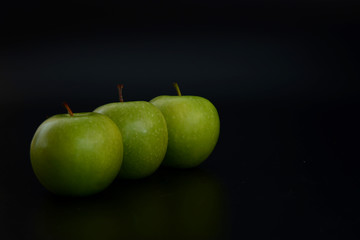 Three green apples on a black background. The insulation on the black. Fruits green apples.Healthy and healthy food. fruits.