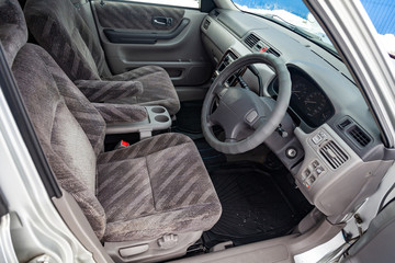 View to the gray color interior of suv car with front seats, steering wheel and dashboard  with striped fabric upholstery after cleaning and detailing in the vehicle repair workshop