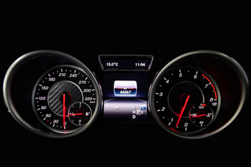 The dashboard of the car is glowing blue with red arrows at night with a speedometer, tachometer...