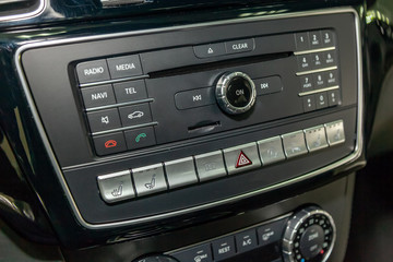 The control panel of the multimedia system, radio, telephone, heated seats and ventilation, emergency stop button and a hole for the memory card on the dashboard of black plastic and chrome luxury car