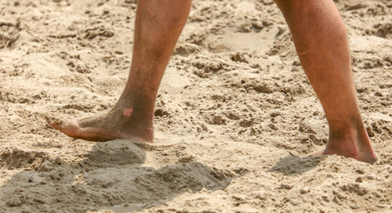 Fototapeta na wymiar Feet of a man in the sand