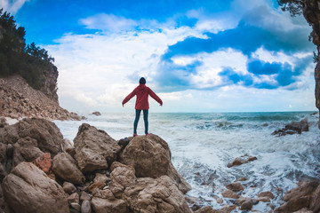 Obraz premium The girl stands on a stone by the sea.