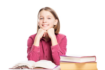 Smiling teen girl sitting at a table with books. Isolated on a white background.