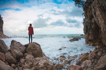 Obraz premium The girl stands on a stone by the sea.