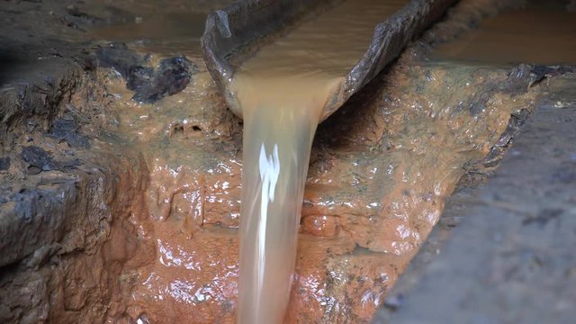 Yellow water flows from the gutter. Drainage system in sewer tunnel, underground river canalization