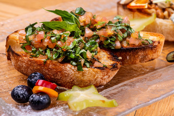 Tasty savory tomato Italian appetizers, or bruschetta, on slices of toasted baguette garnished with basil. Macro.
