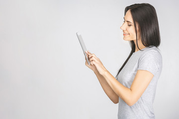 Fototapeta premium Portrait with copy space empty place of pretty charming confident trendy woman in casual having tablet in hands looking at screen isolated on white background.