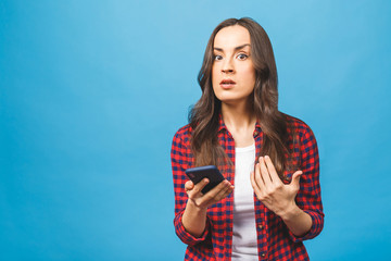 Portrait of a furious caucasian woman talking on mobile phone isolated over blue background. Negative emotions.