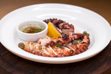 grilled squid rings on a wooden board with sauce