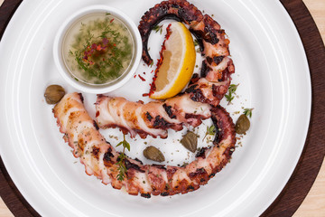 grilled squid rings on a wooden board with sauce