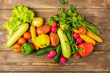 Fresh harvest ripe vegetables zucchini cucumber greens pepper laid out on a wooden background. Healthy food Harvesting.