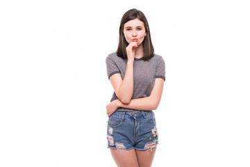 Portrait of a pretty teenage brunette girl posing holding her hand on her chin, looking aside dreaming of something on white background