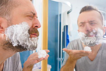 Guy shaving his beard in bathroom