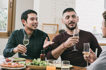 Interracial gay couple having party drinking and eating at home