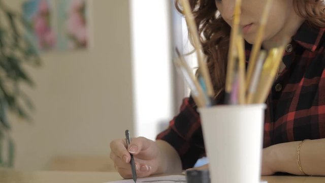 Young pregnant girl draws with pencil in art Studio