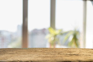 Wood table top on blur of window glass and abstract green from garden with city view in the morning background. For montage product display