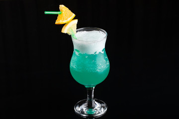 Glass of blue coctail with lemon on elegant dark black background.