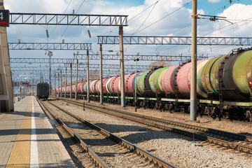 Fototapeta na wymiar Freight train with tanks stands on the rails next to the building of the city station. The train tanks with oil and fuel