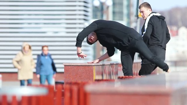 Two young men doing acrobatic parkour tricks. Overcoming obstacles