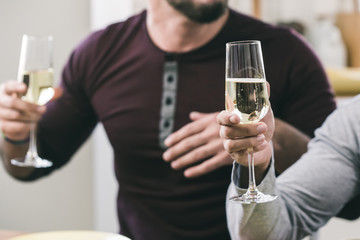 Two male hands holding glasses of sparkling white wine