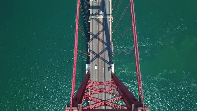 Aerial, birdseye, drone shot, above traffic on road A2 and the Ponte 25 Abril or the Salazar bridge, on a sunny day, on Tejo river, in Lisbon, Portugal
