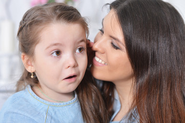 Close up portrait of little girl with mother hugging 