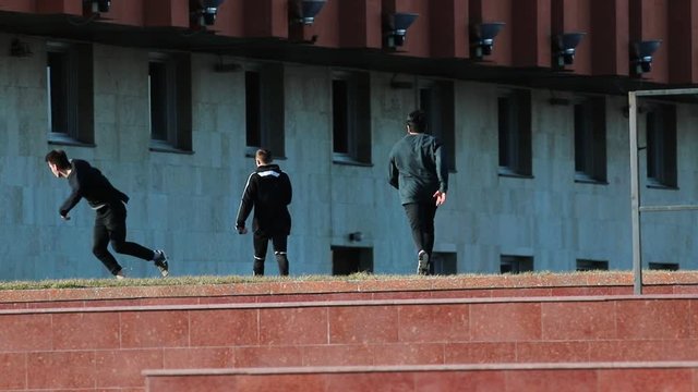 Three athletic young men after overcoming obstacles running forward