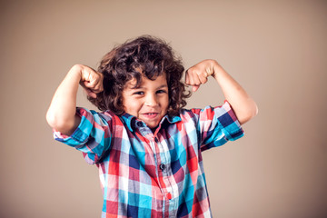 Portrait of a strong kid showing the muscles of his arms