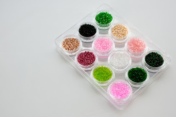 Set of multicolored beads for embroidery and needlework in plastic jars